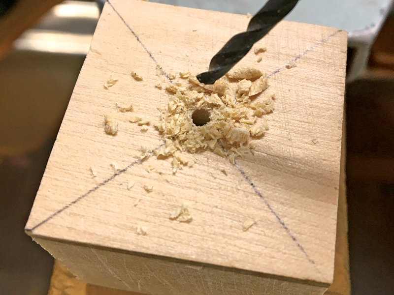 Step 3 drilling a pilot hole in the center of a wooden block