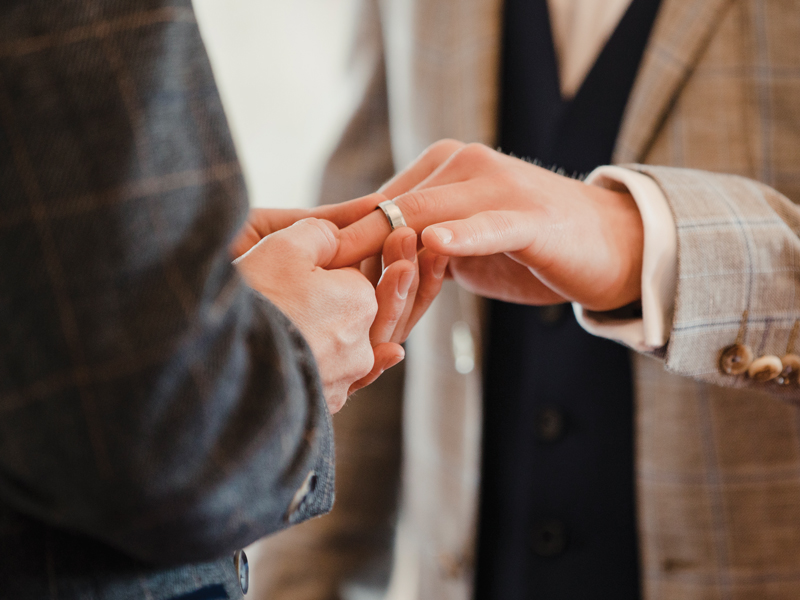 Two men are exchanging rings on their wedding day